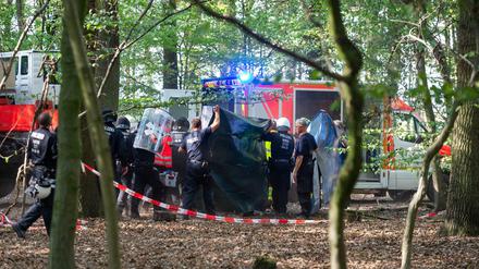 Polizisten und Notärzte bringen einen Journalisten zu einem Krankenwagen, der von einer Hängebrücke im Hambacher Forst gefallen ist.