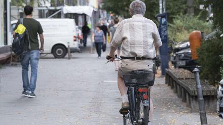 Radfahrer auf Gehweg, von hinten fotografiert.
