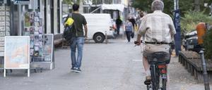 Radfahrer auf Gehweg, von hinten fotografiert.