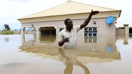 Ein Mann steht vor einem überfluteten Haus in der Nähe der nigerianischen Stadt Lokoja im Wasser.