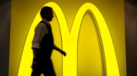 Ein Mann geht am am Logo der Fast-Food-Kette McDonald's vorbei. 