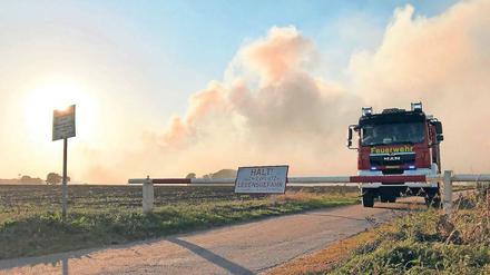 Ein Löschfahrzeug der Feuerwehr steht an einer Schranke zum Gelände.
