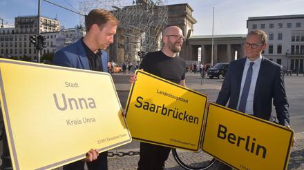 Senatschef Michael Müller (SPD) und Mitorganisatoren der Feiern zeigen drei der 11 040 Ortsschilder, die am 3. Oktober ein „Band der Einheit“ auf dem Festgelände bilden sollen.