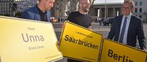Senatschef Michael Müller (SPD) und Mitorganisatoren der Feiern zeigen drei der 11 040 Ortsschilder, die am 3. Oktober ein „Band der Einheit“ auf dem Festgelände bilden sollen.