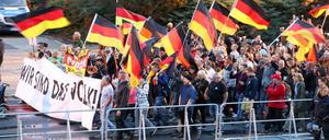 Teilnehmer einer Demonstration der rechtspopulistischen Bewegung Pro Chemnitz ziehen hinter Absperrgittern durch die Stadt.