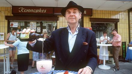 Schauspieler Harald Juhnke, aufgenommen 1991 vor Konnopke's Imbiß in der Weißenseer Mahlerstraße mit Currywurst und einem Glas Berliner Weiße.