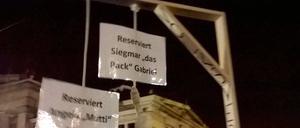 Teilnehmer der einer Pegida Demonstration halten einen gebastelten Galgen hoch.