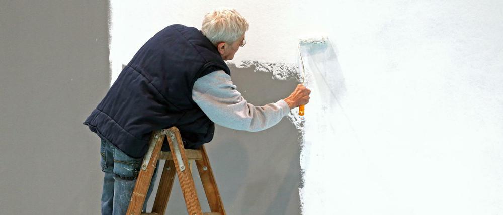 Ein älterer Herr mit grauen Haaren weißt eine Wand auf der Leipziger Messe. 