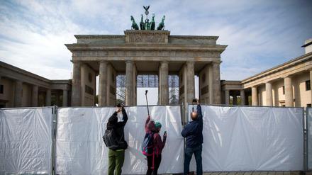 Besucher fotografieren von den Feiern zum Einheitstag über einen Zaun vor dem Brandenburger Tor. 