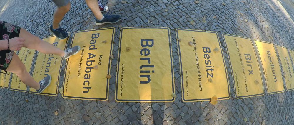 Ein Band der Ortschilder symbolisiert in Berlin die Einheit.
