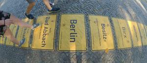 Ein Band der Ortschilder symbolisiert in Berlin die Einheit.