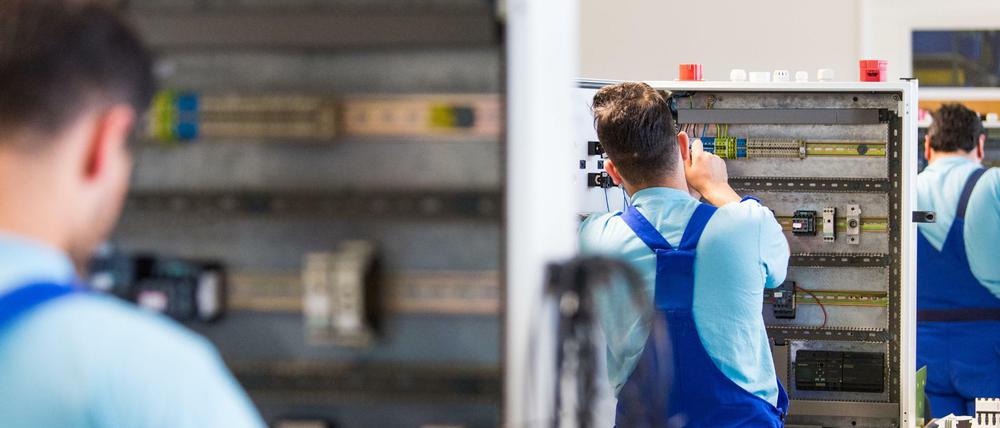 Drei junge Flüchtlinge arbeiten im Ausbildungszentrum der Siemens Professional Education an der Verdrahtung eines Schaltschranks. (Symbolbild)