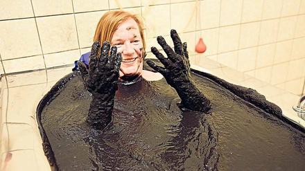 Der Kopf bleibt draußen. Unsere Autorin taucht ein in 220 Liter Moor, die Pampe soll bei vielen Krankheiten lindernd wirken.