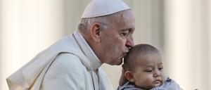 Papst Franziskus küsst ein Kind, als er mit dem Papamobil auf dem Petersplatz ankommt, um seine wöchentliche Generalaudienz im Vatikan abzuhalten. 