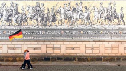 Phantom mit Fahne. Pegida-Anhänger marschieren vor dem historischen Fürstenzug in Dresden. 