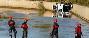 Mallorca: Angehörige der militärischen Nothilfeeinheit Militar de Emergencias (UME) stehen vor einem umgestürzten Auto.