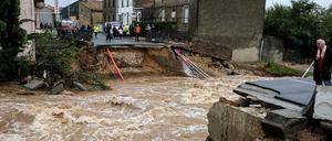 Menschen stehen an einer weggespülten Sraße in Villegeilhenc im Department Aude.