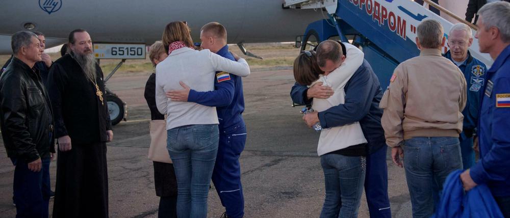 US-Astronaut Nick Hague (Mitte,r) und der russischen Kosmonaut Alexey Ovchinin (Mitte,l) umarmen nach der geglückten Notlandung in Baikonur ihre Angehörigen.