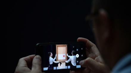 Ein Journalist fotografiert das unfertige Banksy-Werk "Girl with Balloon" 