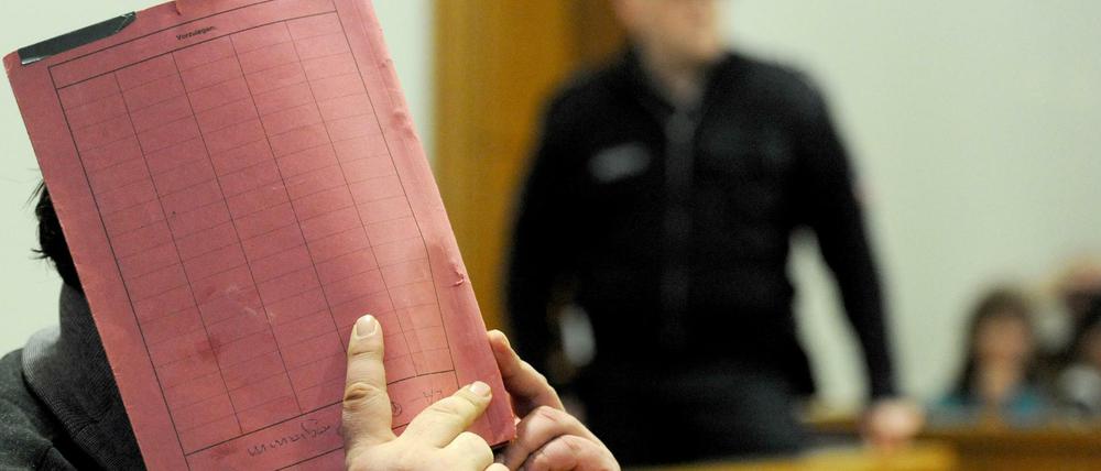  Der ehemalige Krankenpfleger Niels Högel versteckt sein Gesicht hinter einem Aktendeckel, während er auf der Anklagebank des Landgerichts in Oldenburg sitzt.