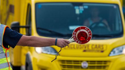 Ein Polizeibeamter mit Kelle steht zu Beginn der Grenzkontrollen durch die bayerische Landespolizei am Grenzübergang Kirchdorf an der Kontrollstelle und winkt Fahrzeuge heraus. +