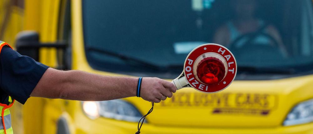 Ein Polizeibeamter mit Kelle steht zu Beginn der Grenzkontrollen durch die bayerische Landespolizei am Grenzübergang Kirchdorf an der Kontrollstelle und winkt Fahrzeuge heraus. +