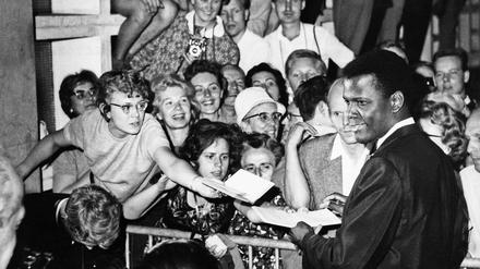 Sydney Poitier auf der Berlinale 1964, umringt von Fans, die zur besseren Sicht die Baukastenfassade der Kongresshalle hochklettern.