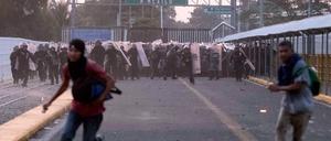 Migranten aus Mittelamerika laufen während Zusammenstößen mit der Polizei nahe der Grenze zwischen Guatemala und Mexiko vor mexikanischen Beamten weg.
