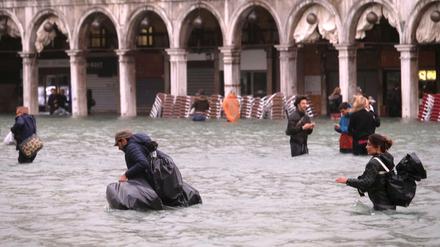 Menschen versuchen, durch das Wasser den Markus-Platz zu überqueren.