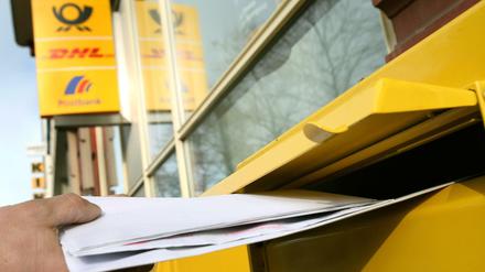 Briefe werden in einen Briefkasten geworfen.