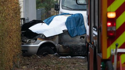 Das ausgebrannte Auto ist mit Tüchern bedeckt.