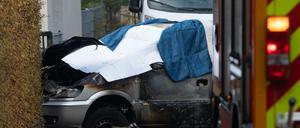 Das ausgebrannte Auto ist mit Tüchern bedeckt.