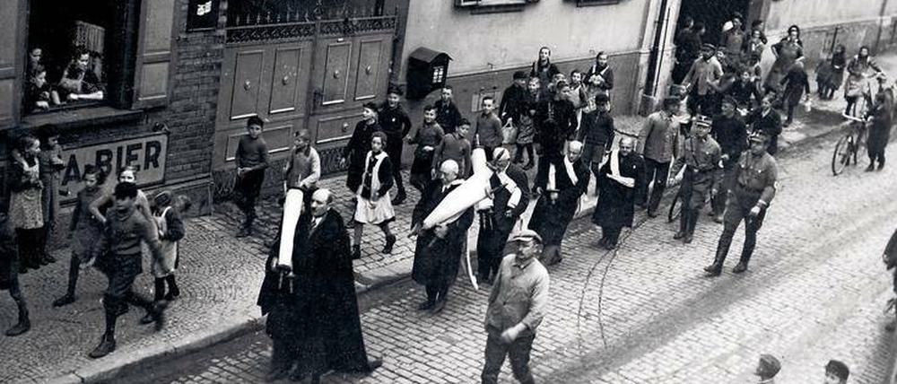 Vor aller Augen. Im rheinhessischen Guntersblum werden jüdische Männer gezwungen, sich zu verkleiden und Thora-Rollen aus der verwüsteten Synagoge durch den Ort zu tragen. Auf dem Marsch wurden sie verhöhnt und gedemütigt. Am Ende mussten sie alles ins Feuer werfen.