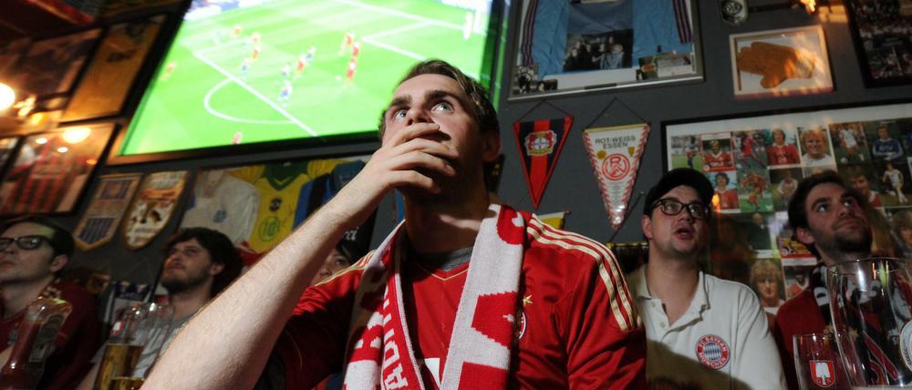 Fans des FC Bayern München gucken in einer Kneipe Fußball.