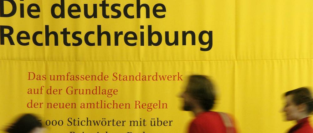 Bei einer Messe sind Passanten vor einem übergroßen Exemplar des Dudens zu sehen.