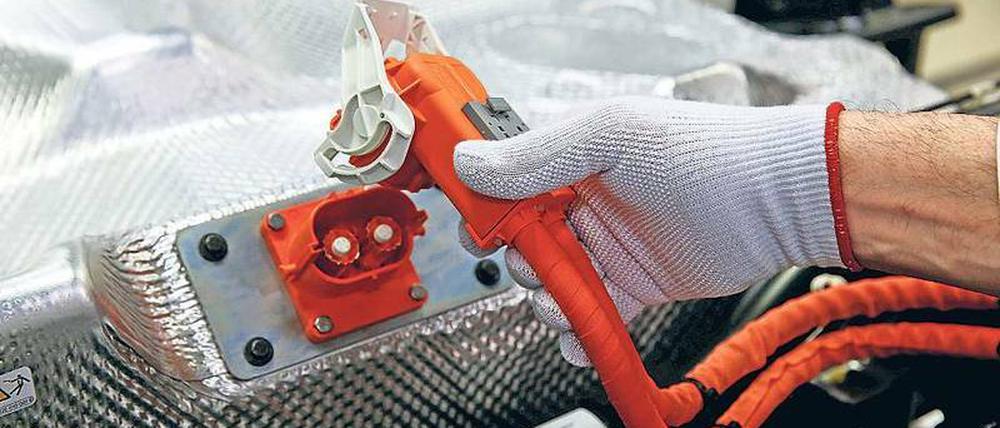 Anschluss finden. Ein VW-Arbeiter montiert eine E-Golf-Batterie.