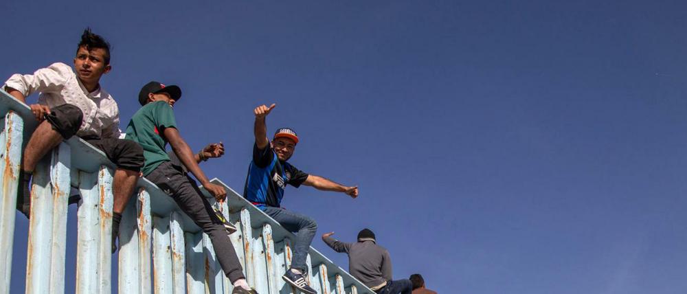 Migranten aus Mittelamerika sitzen nach einer Tausende Kilometer langen Reise auf dem Grenzzaun zwischen Mexiko und den USA.