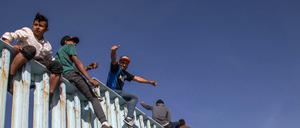 Migranten aus Mittelamerika sitzen nach einer Tausende Kilometer langen Reise auf dem Grenzzaun zwischen Mexiko und den USA.