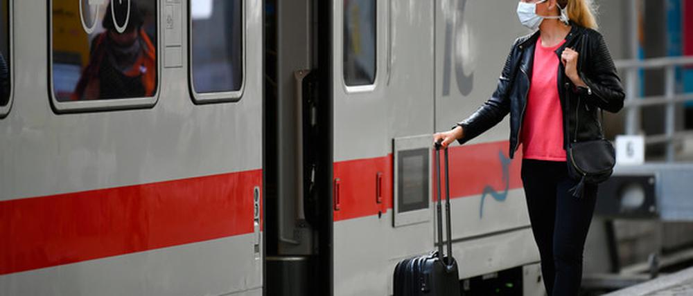 Frau mit Mundschutzmaske wartet auf Zug.