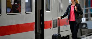 Frau mit Mundschutzmaske wartet auf Zug.