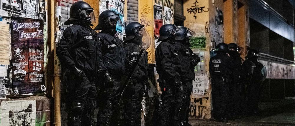 Polizeibeamte stehen bei einer Razzia in der Rigaer Straße in Berlin-Friedrichshain vor einem Haus.