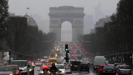 Autos fahren in Paris auf der Avenue des Champs-Élysées auf den Arc de Triomphe zu.
