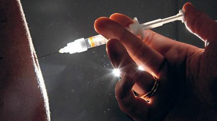 Eine Ärztin spritzt einer Patientin eine Grippeschutzimpfung. 