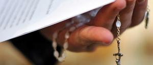 Ein Priester hält einen Rosenkranz und ein Schreiben in der Hand. (Symbolbild)