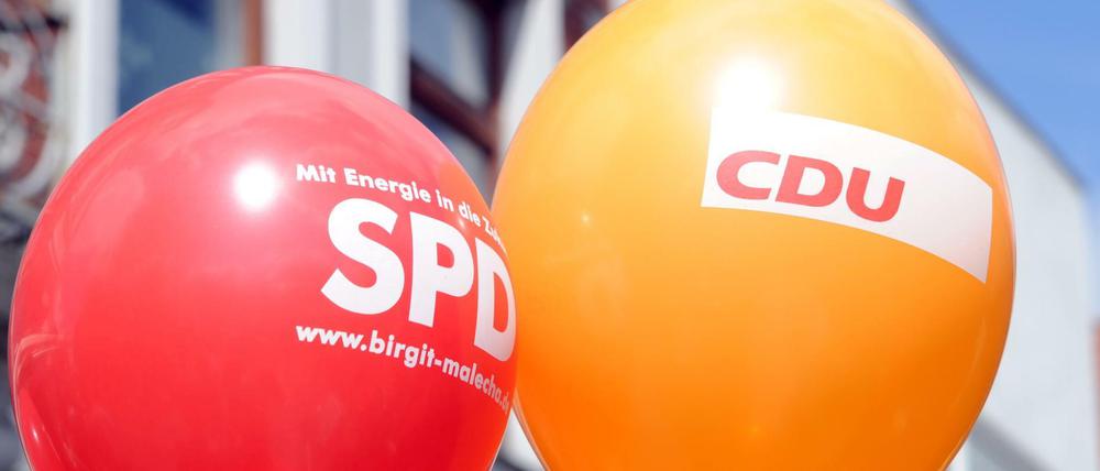 Ein SPD- und ein CDU-Luftballon schweben in der Luft.