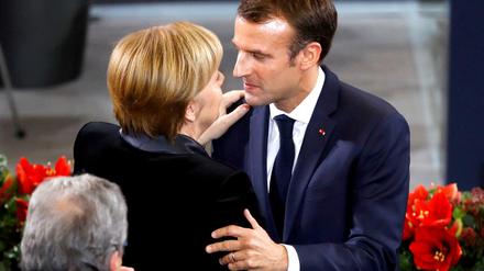 Kanzlerin Merkel und Frankreichs Staatschef Macron begrüßen einander am Sonntag im Bundestag.