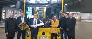 Gruppenbild mit Bus. Fototermin in der BVG-Halle.