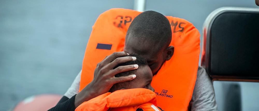 Ein Mann hält seinen Sohn im Arm, nachdem er von Helfern von seinem Schlauchboot im Mittelmeer gerettet wurde.