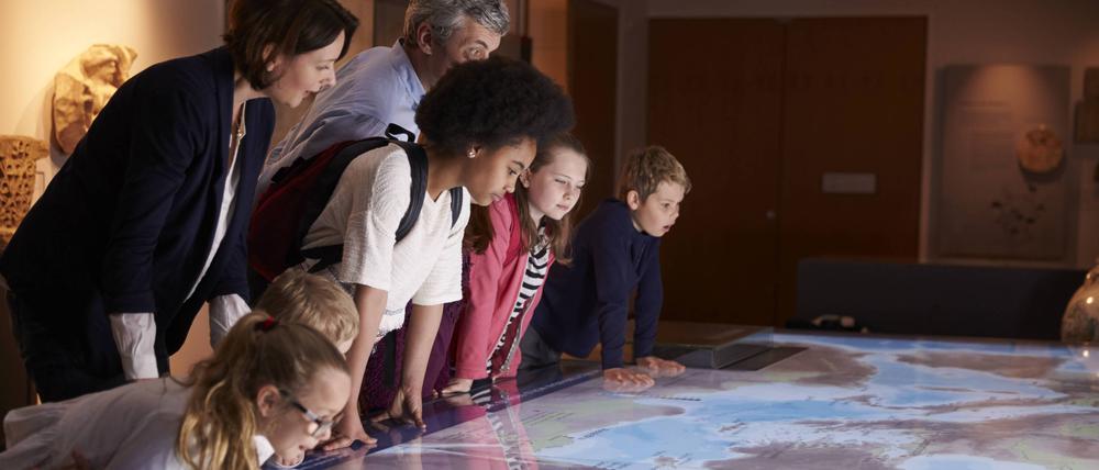 Kinder und Erwachsene schauen sich eine Landkarte im Museum an.