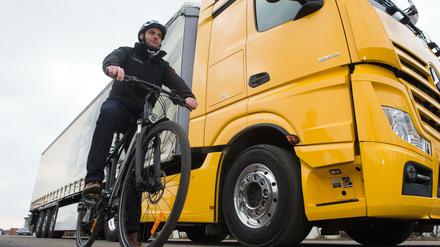 Ein Radfahrer in der Versuchsabteilung von Mercedes neben einem LKW mit Abbiegeassistenten.